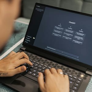 Close-up of a person typing on a laptop displaying the ChatGPT interface, emphasizing modern technology use.